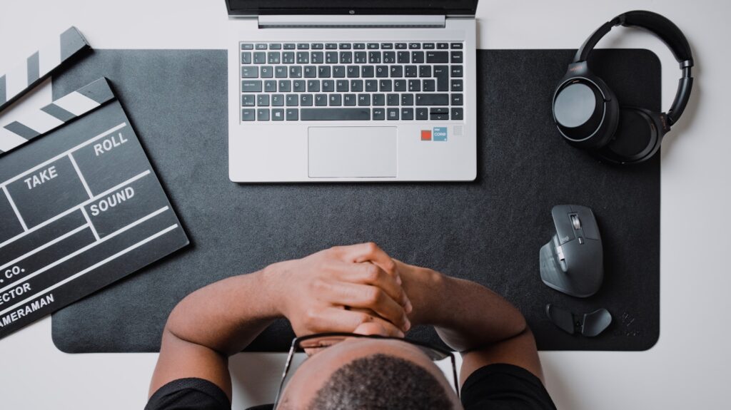 a person sitting at a desk with a laptop and headphones procrastinating